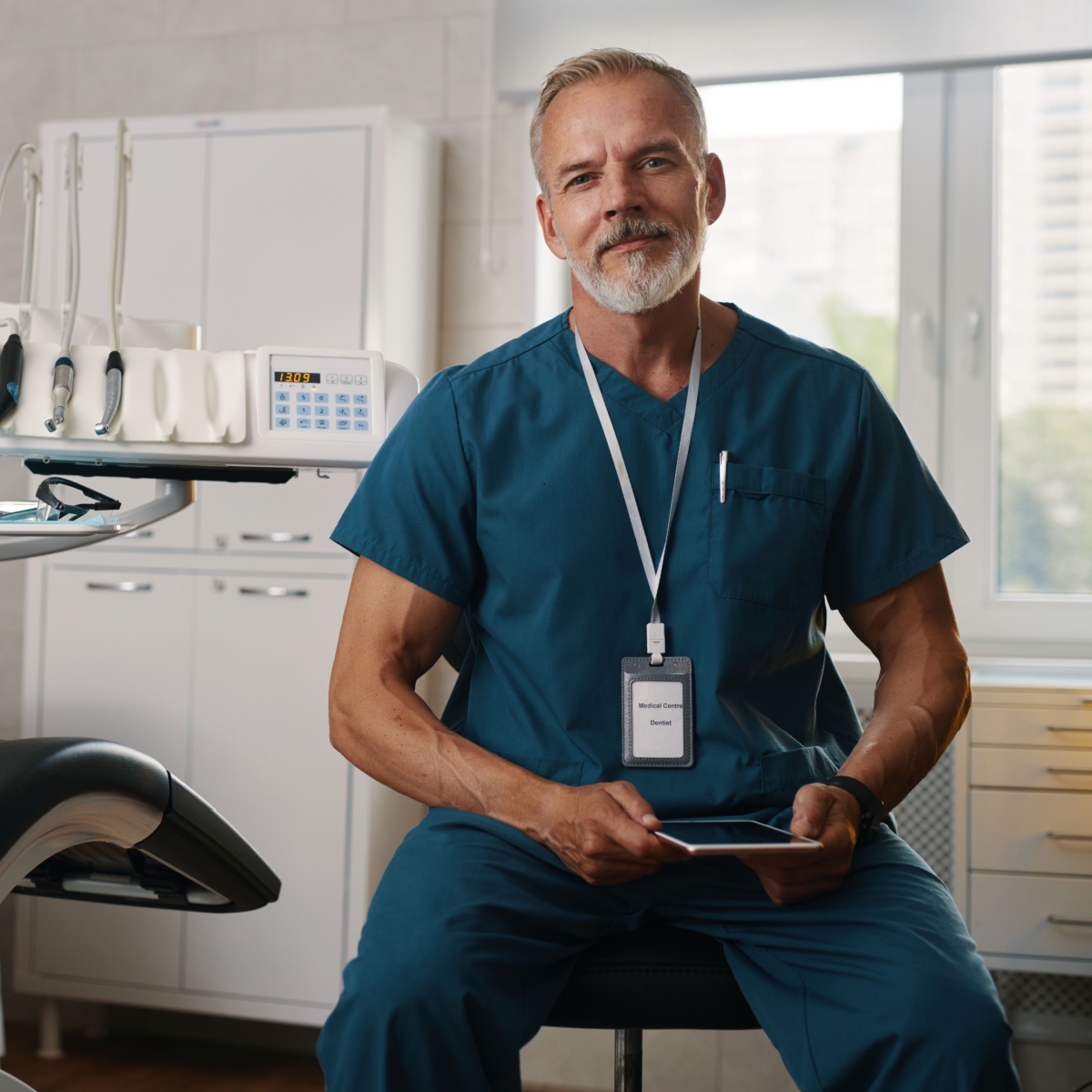 A dentist holding a tablet with the OrthoPhoto app